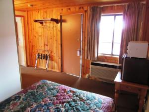 1 dormitorio con cama, ventana y puerta en Travelers Lodge, en West Yellowstone