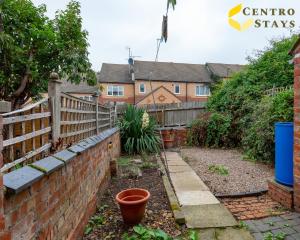 a garden with a brick wall and a fence at Families Groups Contractors Relocation Free Parking & WiFi in Northampton