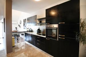 een grote keuken met zwarte kasten en een wastafel bij Luxury apartment Duće with private pool in Omiš
