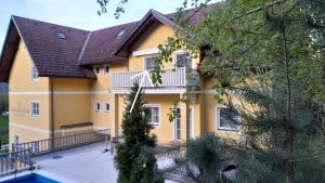 a yellow house with a balcony and a swimming pool at Glanz und Gloria Velden! Wörthersee in 5 min zu Fuß erreichbar! in Velden am Wörthersee