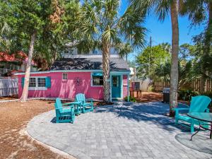 une maison rose avec des chaises bleues et des palmiers dans l'établissement Surf Puppy, à Tybee Island