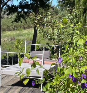 a white bed sitting on a deck with purple flowers at Dominio Vale Flores in Advagar