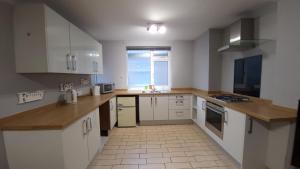 a kitchen with white cabinets and a large window at Fully Furnished 3 bedroom Appartment in Bristol