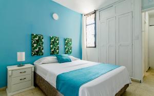 a blue bedroom with a large bed and a window at La Mochila SM in Santa Marta