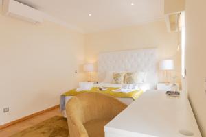 a white bedroom with a bed and a table at Sunny, The House - AL in Faro