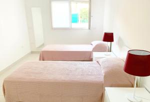 two beds in a white room with a window at Casa Baroncini Appartamenti in Cervia +7 photos