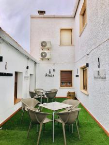 a patio with tables and chairs on the grass at Hostal El Bomba 