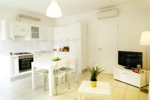 uma cozinha com armários brancos e uma mesa e cadeiras brancas em Casa Baroncini Appartamenti em Cervia