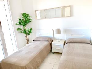 two beds in a room with a plant on the wall at Casa Baroncini Appartamenti in Cervia
