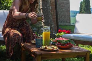 a woman pouring a drink on a table with food at Agriturismo Quarantallina in Buonconvento