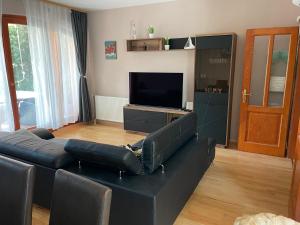 uma sala de estar com um sofá preto e uma televisão em Marina Apartman em Siófok