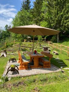 a picnic table with an umbrella and a bench at Waldhütte Glück Auf in Nötsch bei Bleiberg