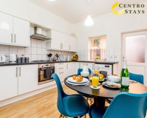 a kitchen with a table and blue chairs in a room at 5-10 Off Weekly-Monthly Stays for Groups, Family Relocation, Contractors or Corporate bookings in Northampton