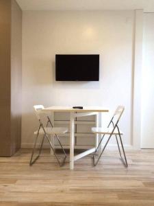 mesa blanca con 2 sillas y TV en la pared en Cozy Apartment in Historical Center, en Viana do Castelo 4 fotos más