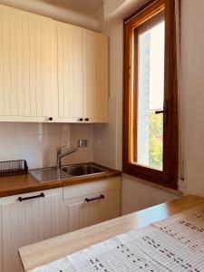 a kitchen with white cabinets and a sink and a window at Jo's House in Calambrone