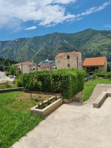 a park with a hedge and some buildings and mountains at Apartments Marina in Kotor