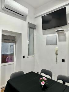 une salle à manger avec une table noire et une télévision dans l'établissement Love Pink Gran Via, à Madrid