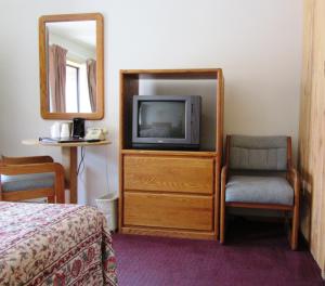 una camera con TV, sedia e specchio di Travelers Lodge a West Yellowstone