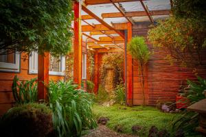 einen Garten mit einer Pergola neben einem Haus in der Unterkunft Hotel Departamentos del Sur in Puerto Montt