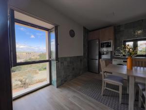 eine Küche mit einem Tisch und einem großen Fenster in der Unterkunft Casalagata in Alcántara