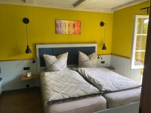a bedroom with a bed with yellow walls at Lütte Uttiet in Stelle-Wittenwurth