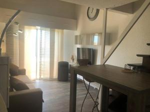 a living room with a table and a clock on the wall at F2 F3 en duplex Port-Frejus proche de la mer in Fréjus