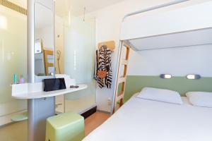 a bedroom with a bed and a desk with a mirror at ibis budget Perpignan Centre in Perpignan