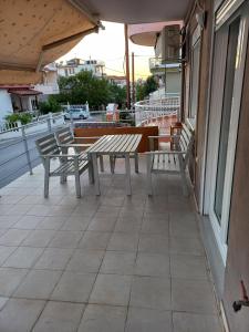 a patio with benches and tables on a balcony at dimis apartment in Nea Michaniona