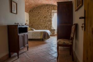 a bedroom with a bed and a tv and a chair at Mas Solés in Parlavà