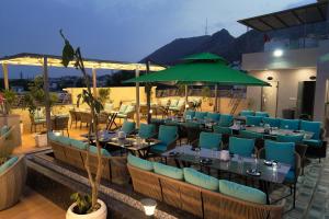 ein Restaurant mit Tischen und Stühlen und einem grünen Sonnenschirm in der Unterkunft HOTEL AJMER SHERATON in Ajmer