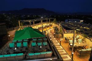 a rooftop patio with a green umbrella and tables and chairs at HOTEL AJMER SHERATON in Ajmer