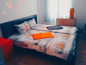 a bed with an orange blanket and a laptop on it at STUDIO Eva in Sajmište