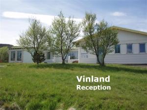 a white house with trees in a yard at Vinland Camping Pods in Egilsstaðir
