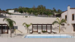 ein Gebäude mit einem Pool und Palmen in der Unterkunft Manificus Villas, Designed for Togetherness, By ThinkVilla in Palaiokastro
