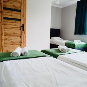 2 Betten in einem Zimmer mit weißer Bettwäsche und Handtüchern in der Unterkunft Zielony Zakątek Przeciszów Zator in Przeciszów