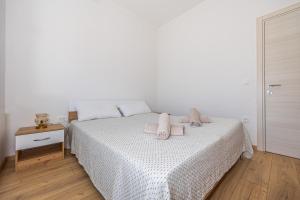 biała sypialnia z łóżkiem z różowymi ręcznikami w obiekcie Happy Holiday w mieście Dramalj