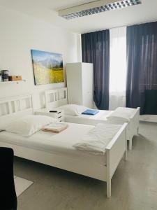 3 weiße Betten in einem Zimmer mit blauen Vorhängen in der Unterkunft Apartments Mainz in Mainz