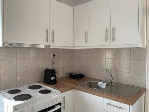 a kitchen with white cabinets and a stove and a sink at Vryzas Resort in Ofrínion