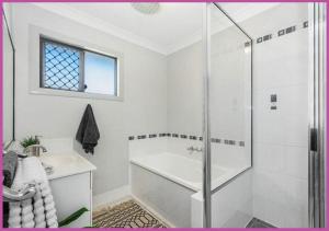 a white bathroom with a shower and a tub and a sink at Sarina Court 8 in Ross River