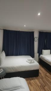- 2 lits dans une chambre dotée de rideaux bleus dans l'établissement City Sparrow Apartment 3, à Londres
