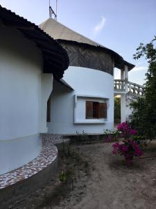 une maison blanche avec une fenêtre et des fleurs violettes dans l'établissement Karamba Lodge, à Kafountine