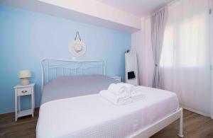 niebieska sypialnia z łóżkiem z ręcznikami w obiekcie Laconian Collection Cosy House in the heart of Gytheio w mieście Gythio