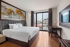een slaapkamer met een bed, een bureau en een raam bij 22Land Residence Hotel & Spa Ha Noi in Hanoi