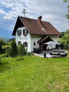 uma grande casa branca com um pátio e guarda-chuva em SapplAlm em Millstatt