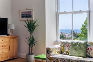 - un salon avec un canapé et une fenêtre dans l'établissement Manacles - Spacious flat near beach with sea views & parking, à Falmouth