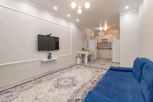 een woonkamer met een blauwe bank en een flatscreen-tv bij Евродвушка в ЖК Orynbor Towers in Astana