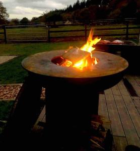 a fire pit sitting on a table in a yard at Cottage cocooning romantique avec jaccuzzi privé in Ancinnes