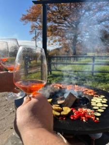 a person holding a glass of wine next to a grill at Cottage cocooning romantique avec jaccuzzi privé in Ancinnes