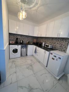 a kitchen with white cabinets and a washer and dryer at Midtown Apartment in Kŭrdzhali