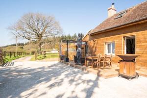 een houten huis met een tafel en stoelen buiten bij Relaxing cottage bain nordique in Ancinnes